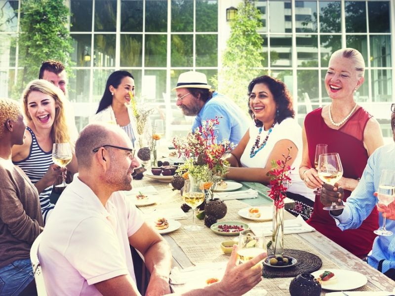 People socialising round table with snacks and wine