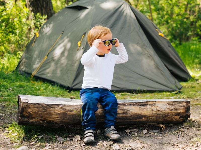 Child outdoors sat on log