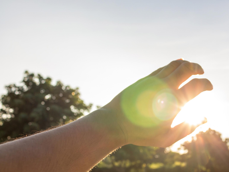 Someone shielding their eyes from the glare of the sun with their hand.