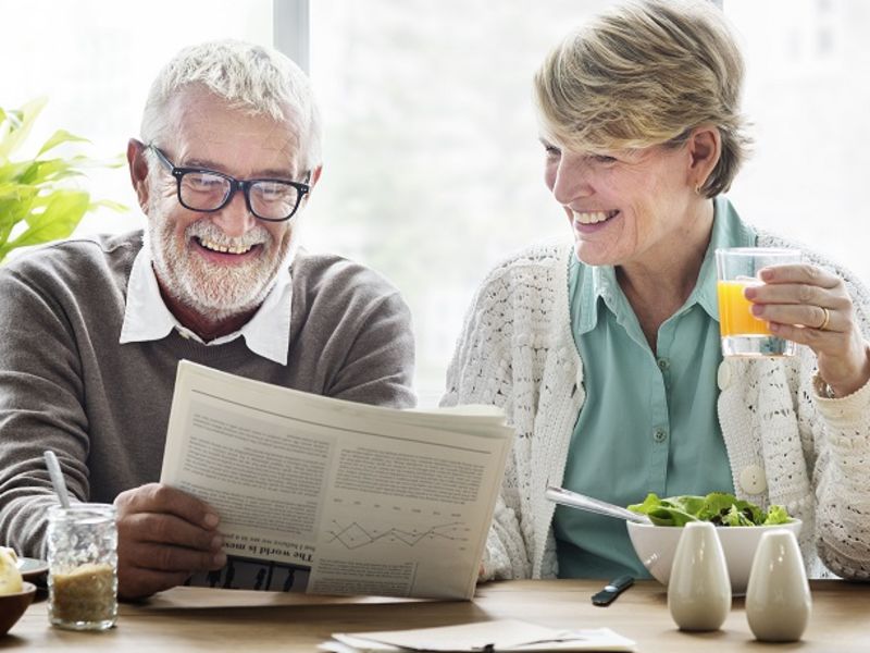 Man and woman smiling reading newspaper