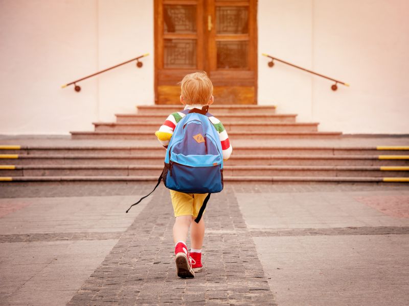 Child with rucksack walking into school