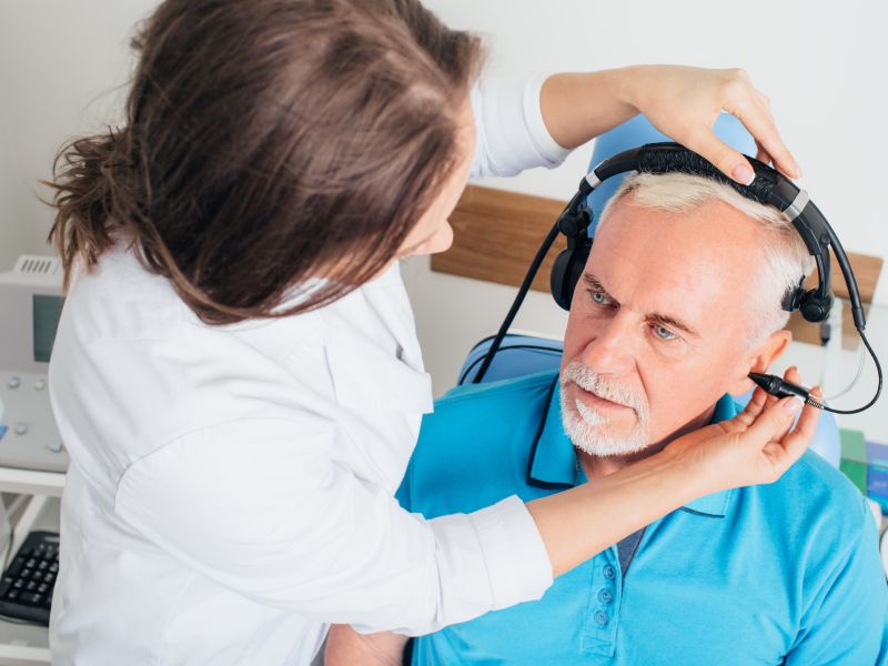 an audiologist testing elderly man's hearing