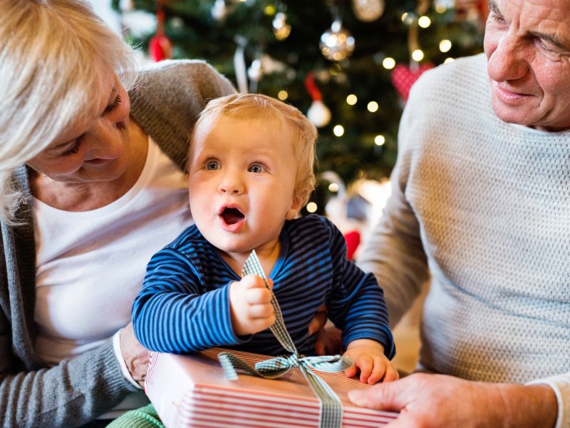 Two adults and baby unwrapping Christmas present