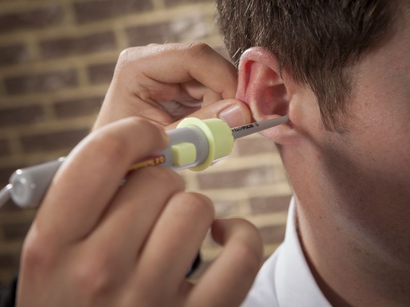 Man probing ear with ear wax cleaner