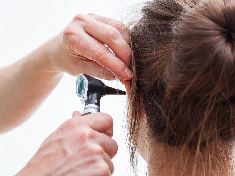 Man inspecting inside of woman's ear