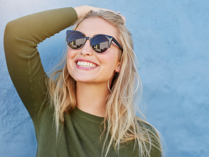 Woman wearing sunglasses with painted blue wall background