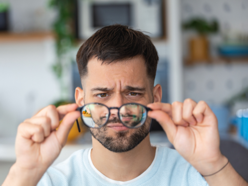 A confused man looking at his glasses.