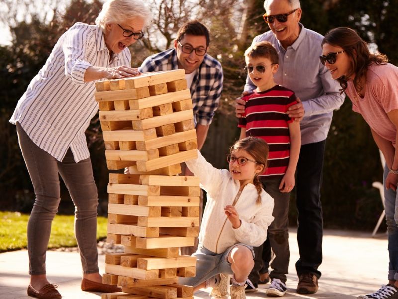 Child knocking over Jenga playing with family