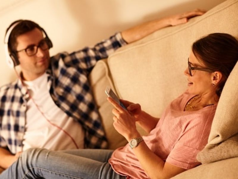 Woman laid down with legs over man in headphones