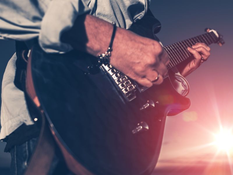 Man playing guitar with sunset backdrop