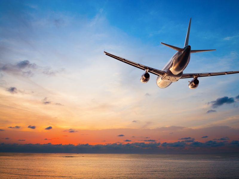 Plane flying towards sunset