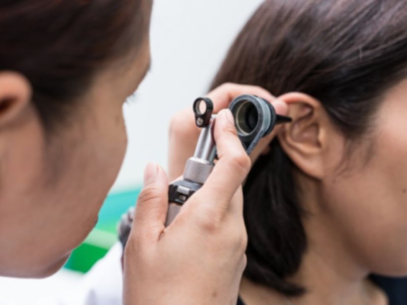 Man inspecting inside of woman's ear