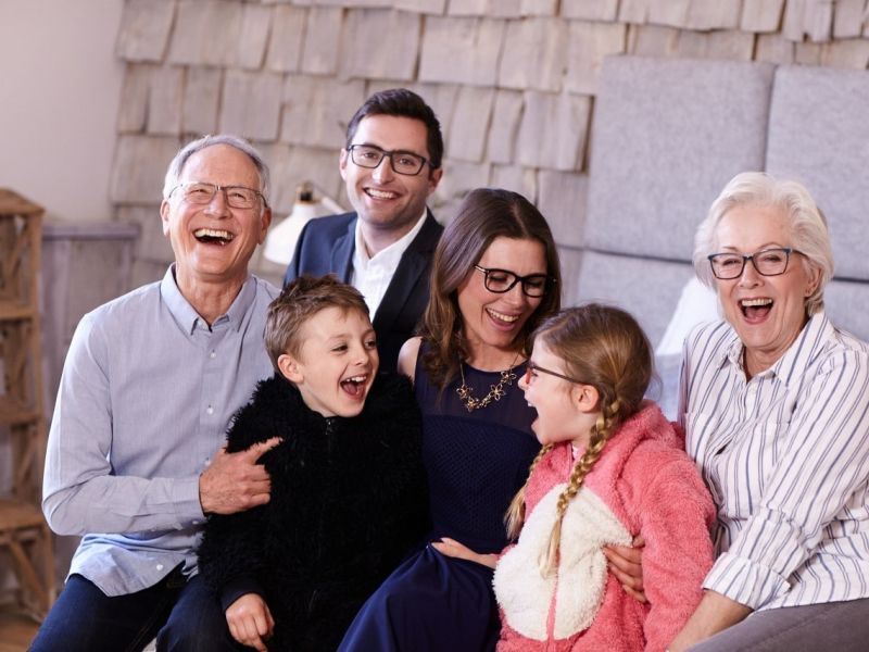 Three generation family sat on bed laughing