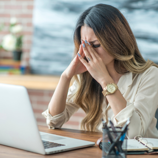 A woman looking stressed at her desk.