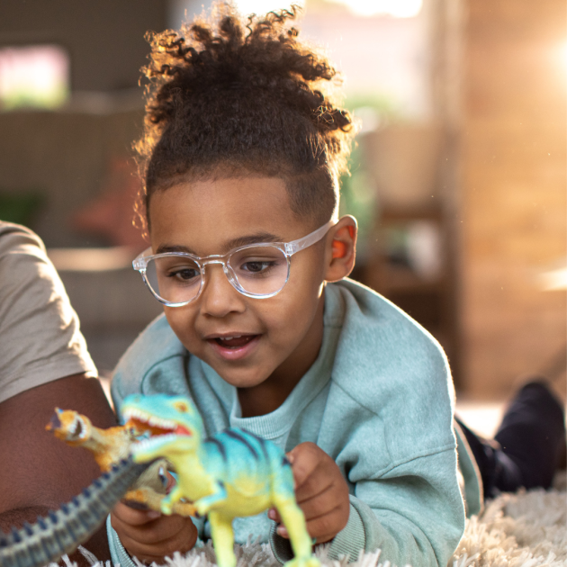 A child wearing glasses and playing with toys.