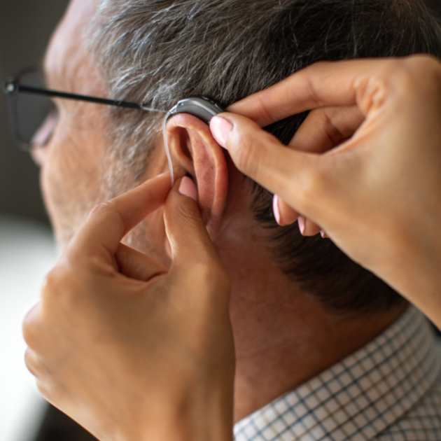 A man having an hearing aid putting on