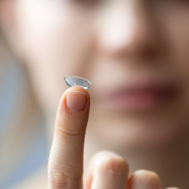 A woman holding a small contact lens in her hand.