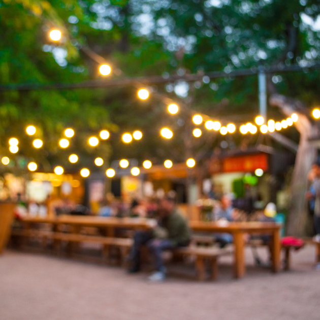 Blurred view of a short-sighted person looking at an illuminated garden with two people sitting at a large table.