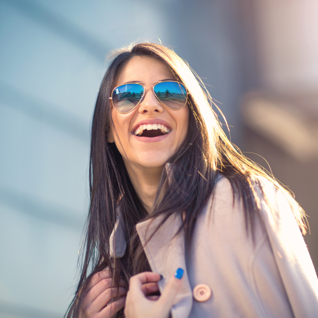 A woman wearing sunglasses and smiling.