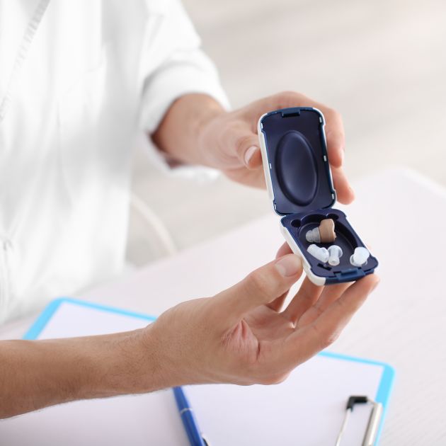 Audiologist offering a hearing aid