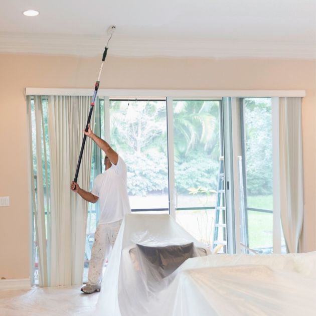 A man painting the ceiling.