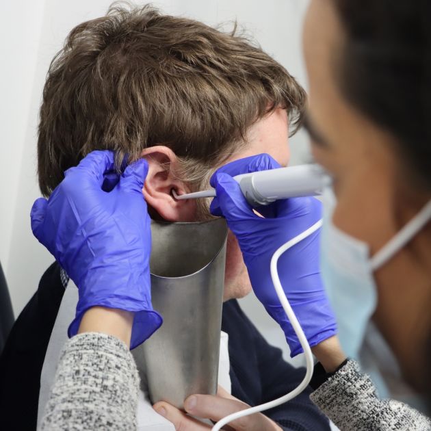 An audiologist performing water irrigation on a patient.