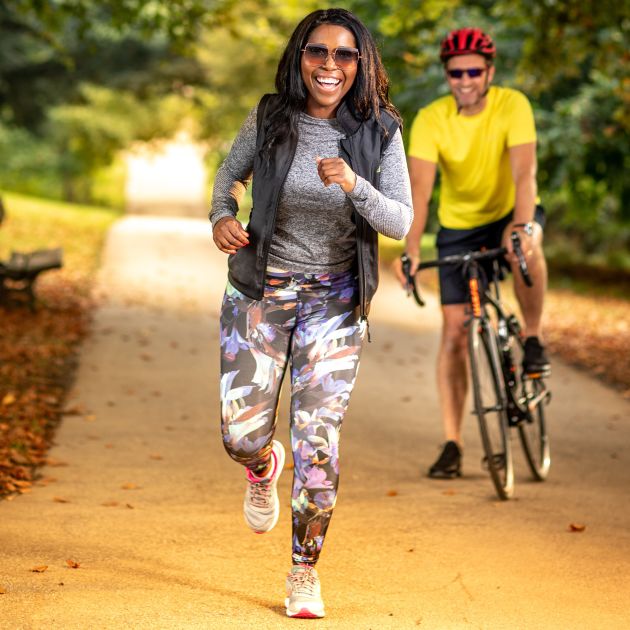 woman running with husband cycling in autumn