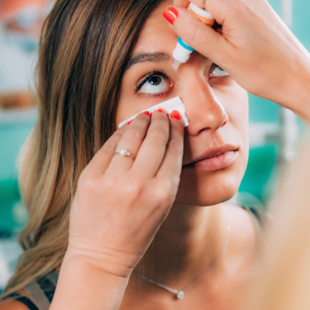 An eye doctor putting eye drops on a patient's eyes.