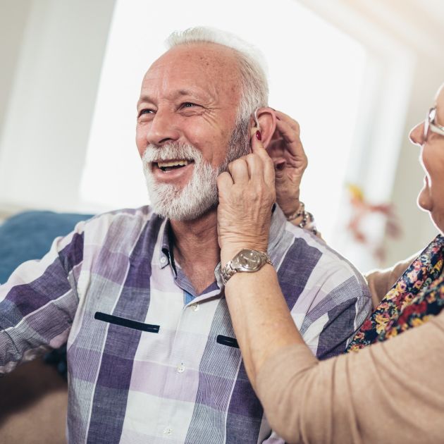 Elderly couple fitting a hearing aid