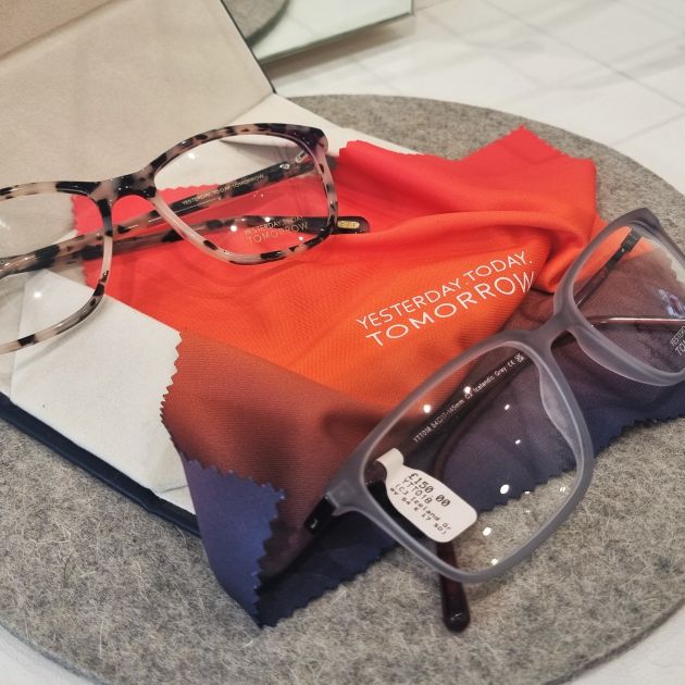 Two pairs of glasses with a glasses cleaning cloth that reads "Yesterday Today Tomorrow."