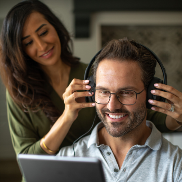 Woman putting hearing equipment on a man