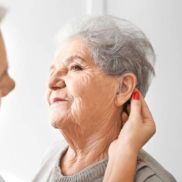 elderly woman having hearing aid fitted