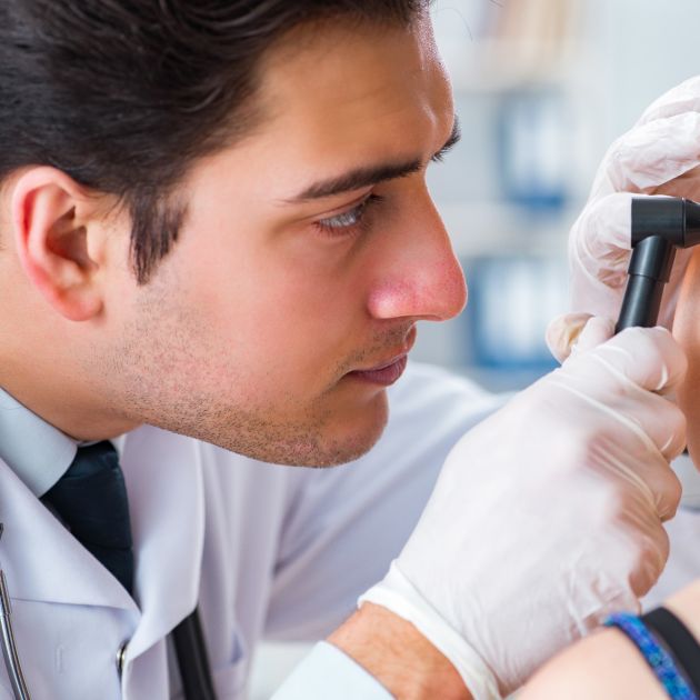 male audiologist checking inside a patient's ear