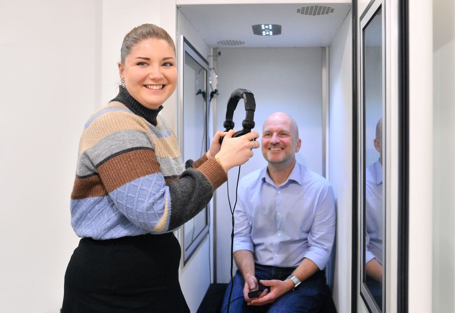Audiologist preparing a patient for a comprehensive hearing test, adjusting equipment and ensuring a comfortable setup.