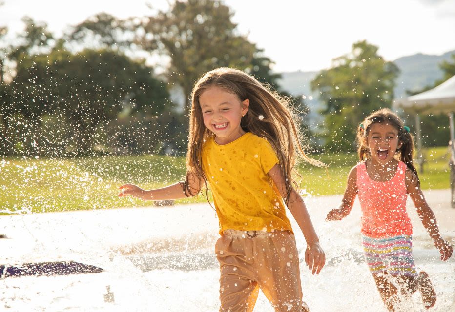 Two girls playing in the water outdoors, enjoying a sunny day with splashes and laughter.