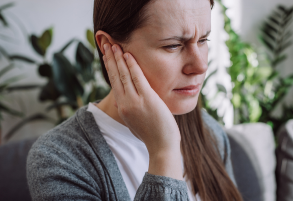 Woman touching her ear with a pained expression.