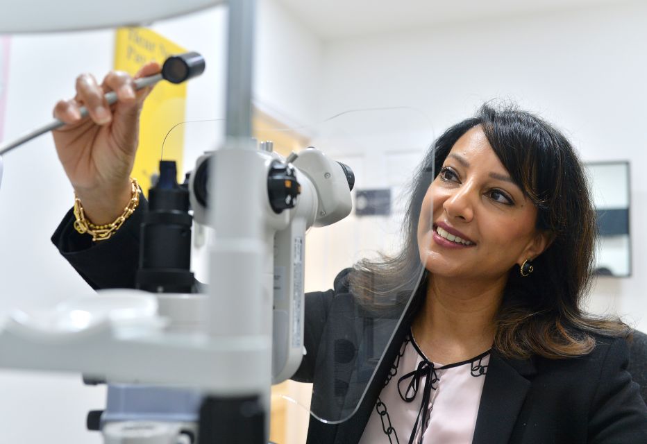 Optometrist preparing the slit lamp machine for an eye examination, adjusting settings and ensuring proper alignment.