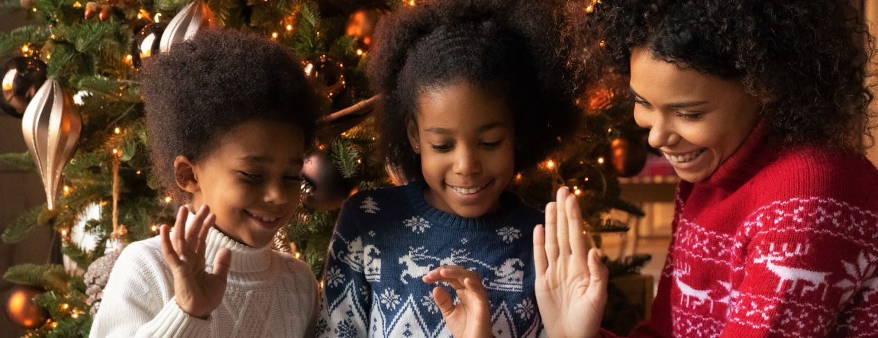 family waving at a video chat on the ipad by the christmas tree
