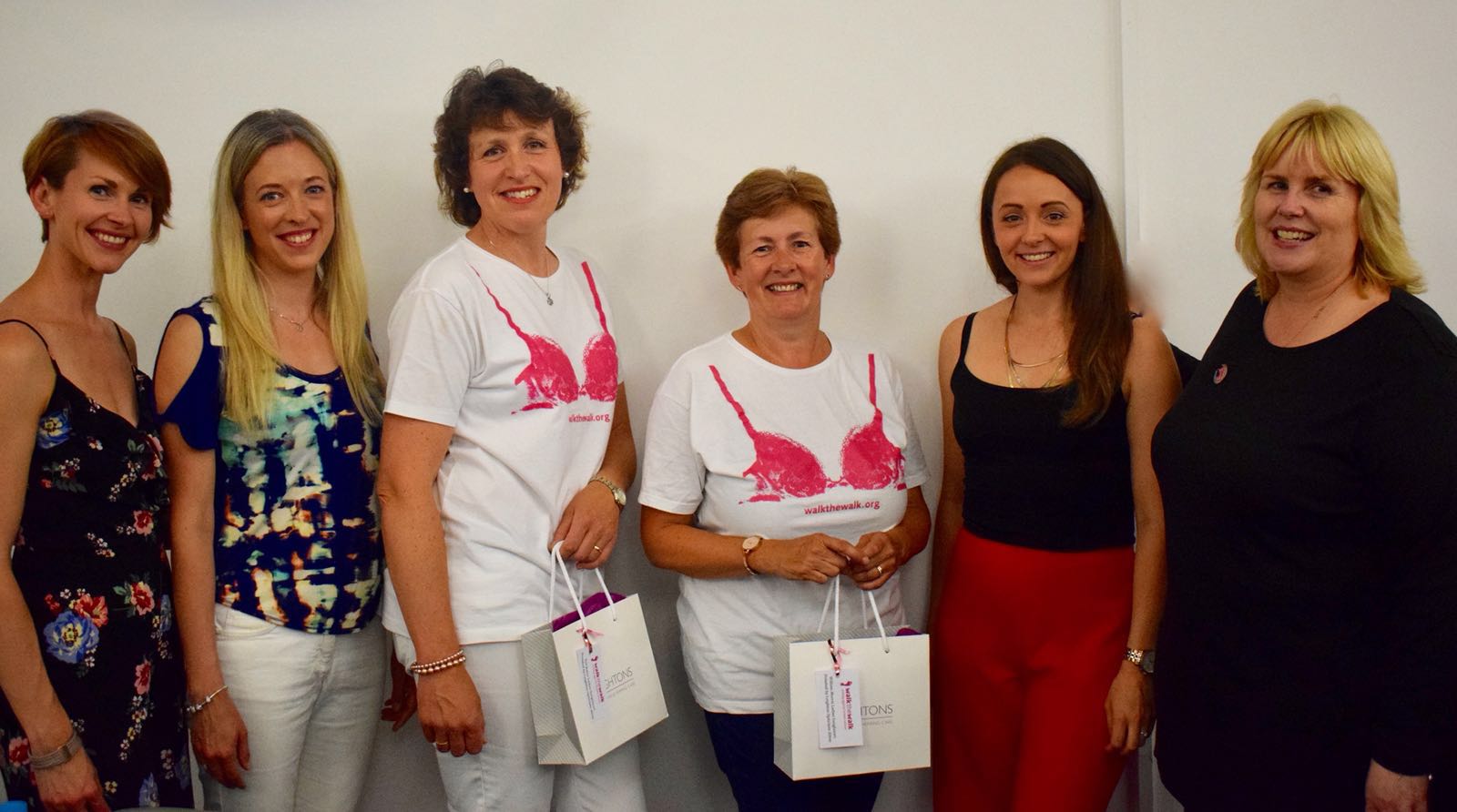 Six women smiling with two wearing a white Walk The Walk t-shirt.