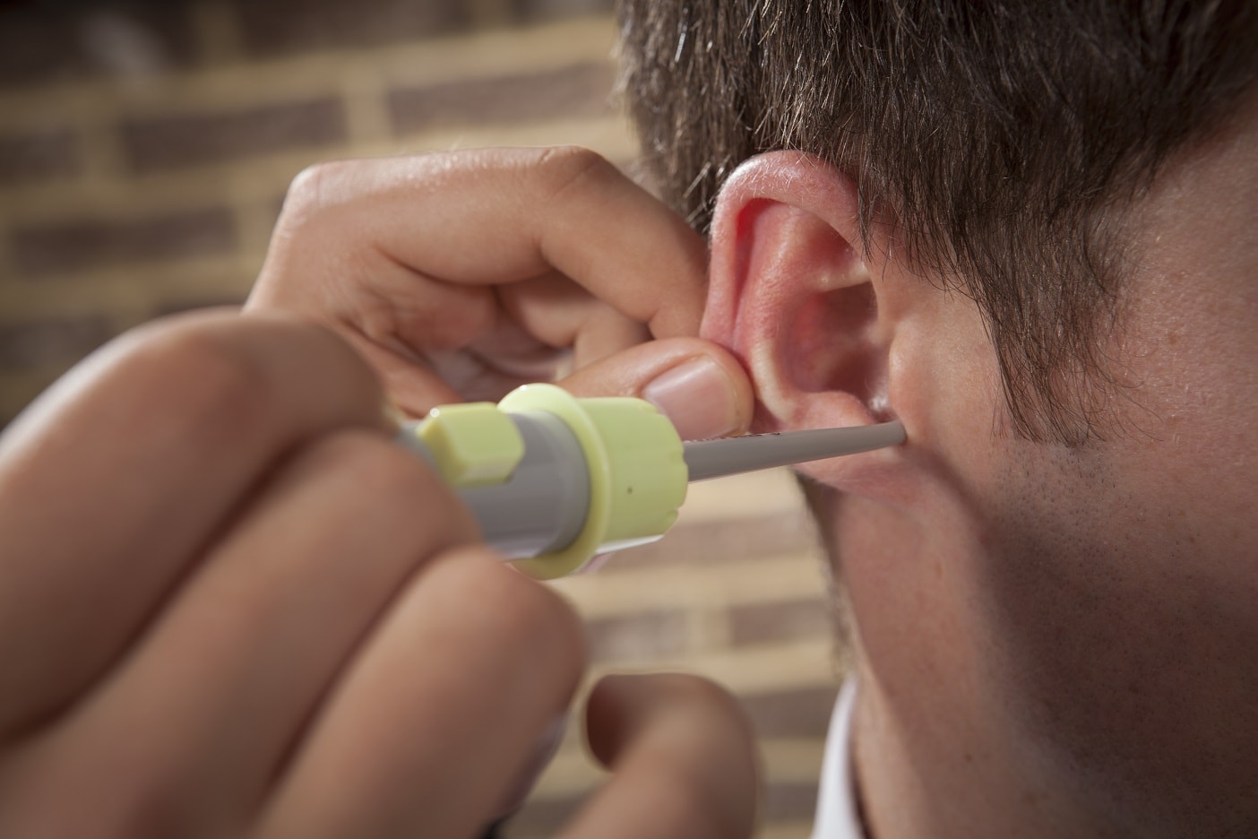 An audiologist performing manual ear wax removal on a patient.