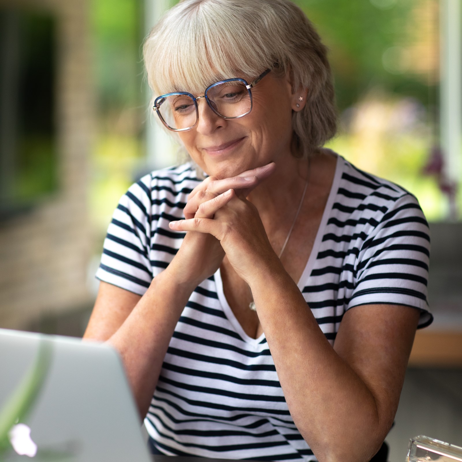 An older woman using a laptop at home.