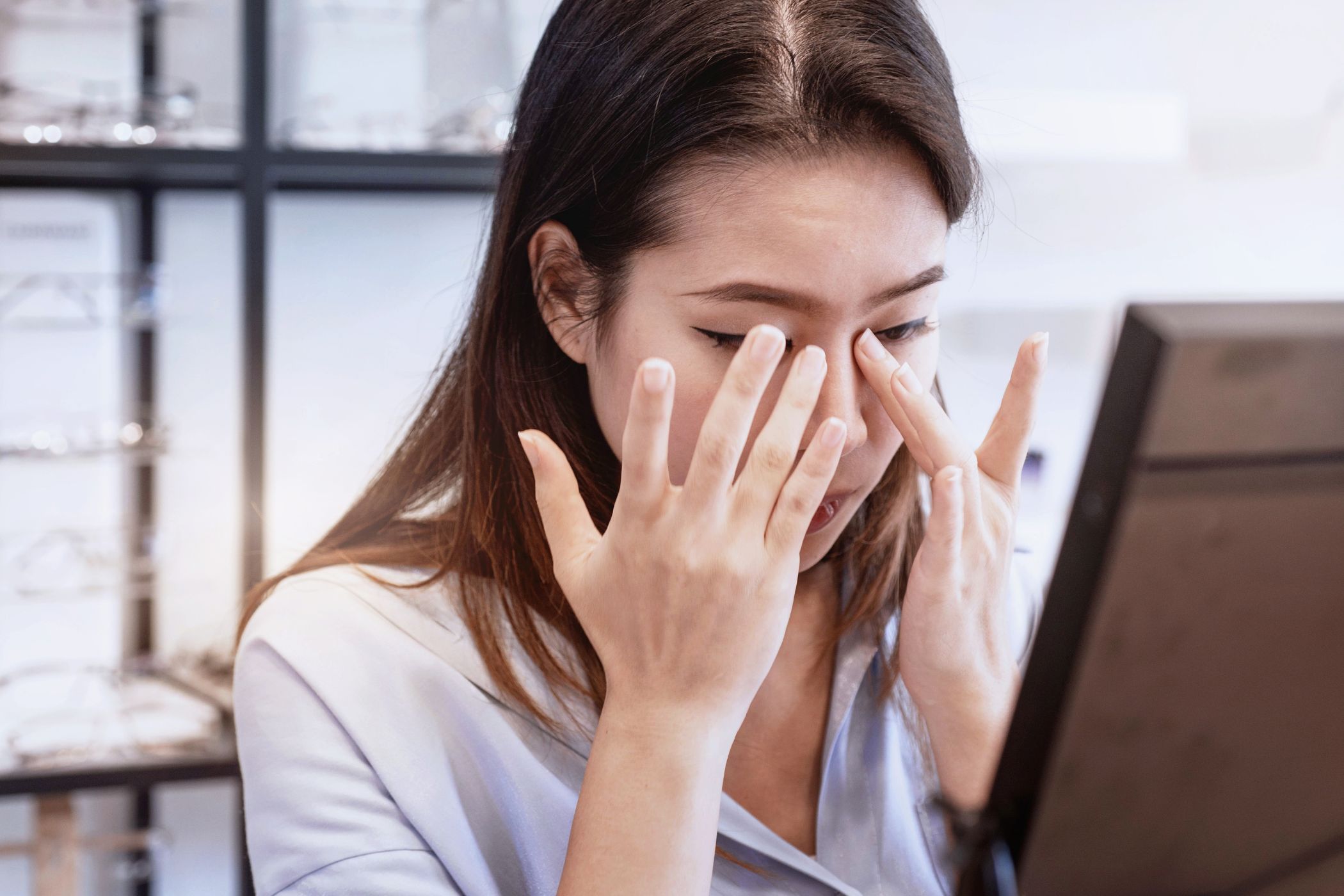 A woman experiencing eye irritation and discomfort after wearing a new pair of contact lenses.