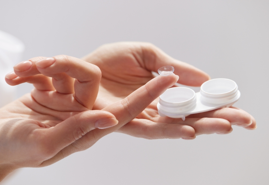 A woman holding a contact lens on her index finger.