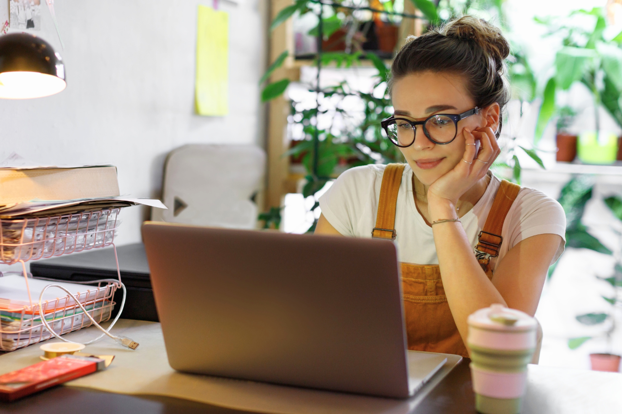 Woman sitting at her desk wearing glasses while using a laptop.