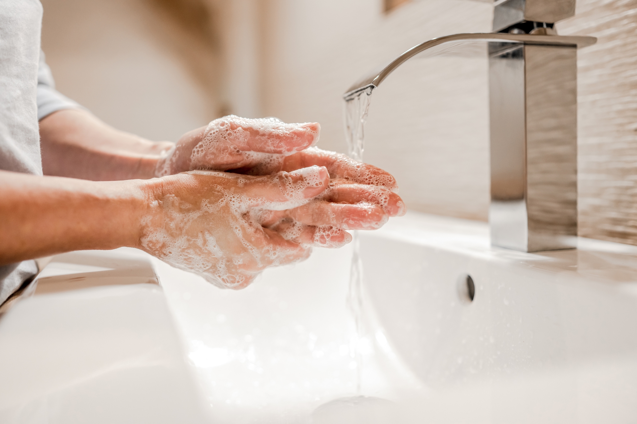 Girl washing her hands with soap, creating foam.