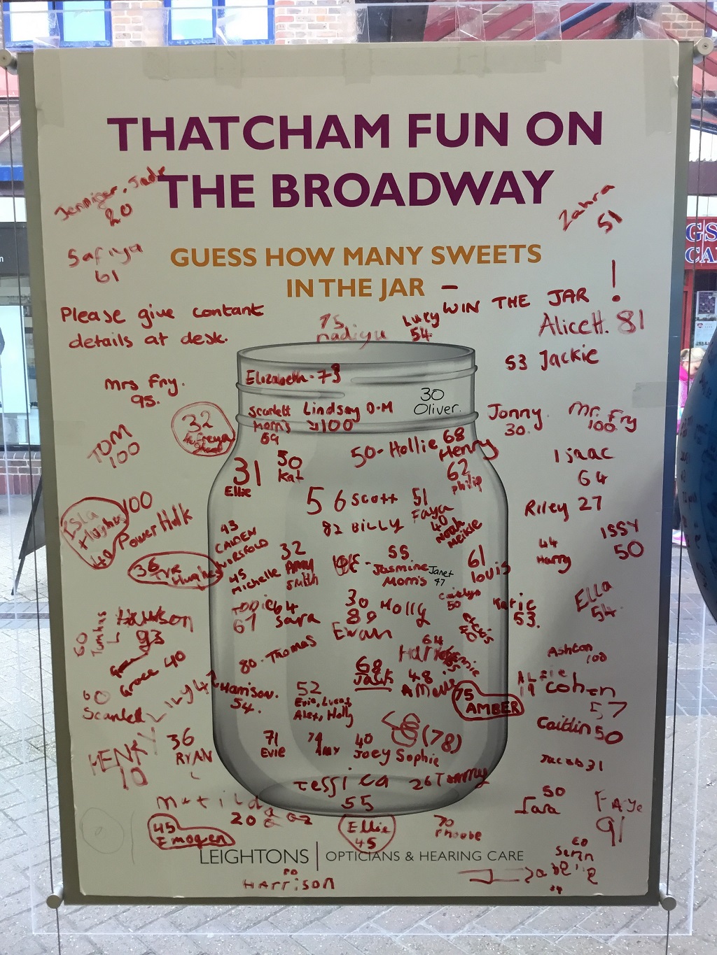 A whiteboard displaying people's guesses of how many sweets are in the jar.