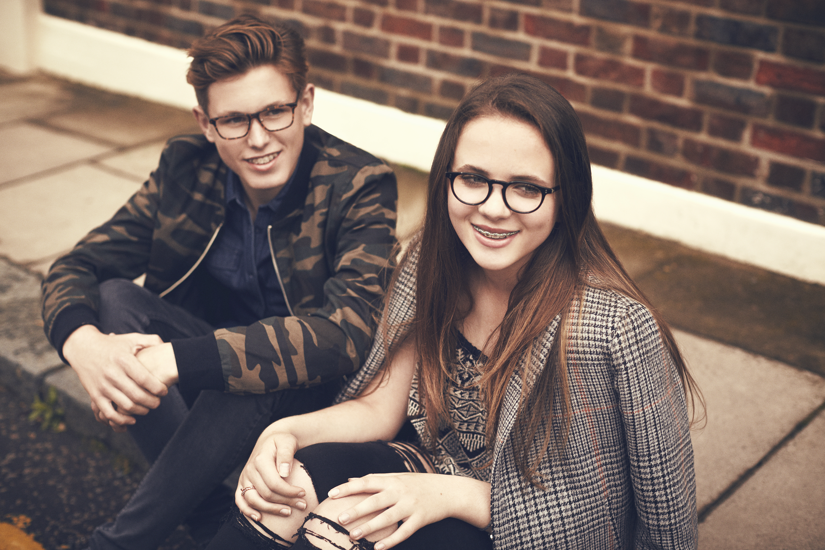 Teenagers wearing Young Wills Eyewear sitting in a street.