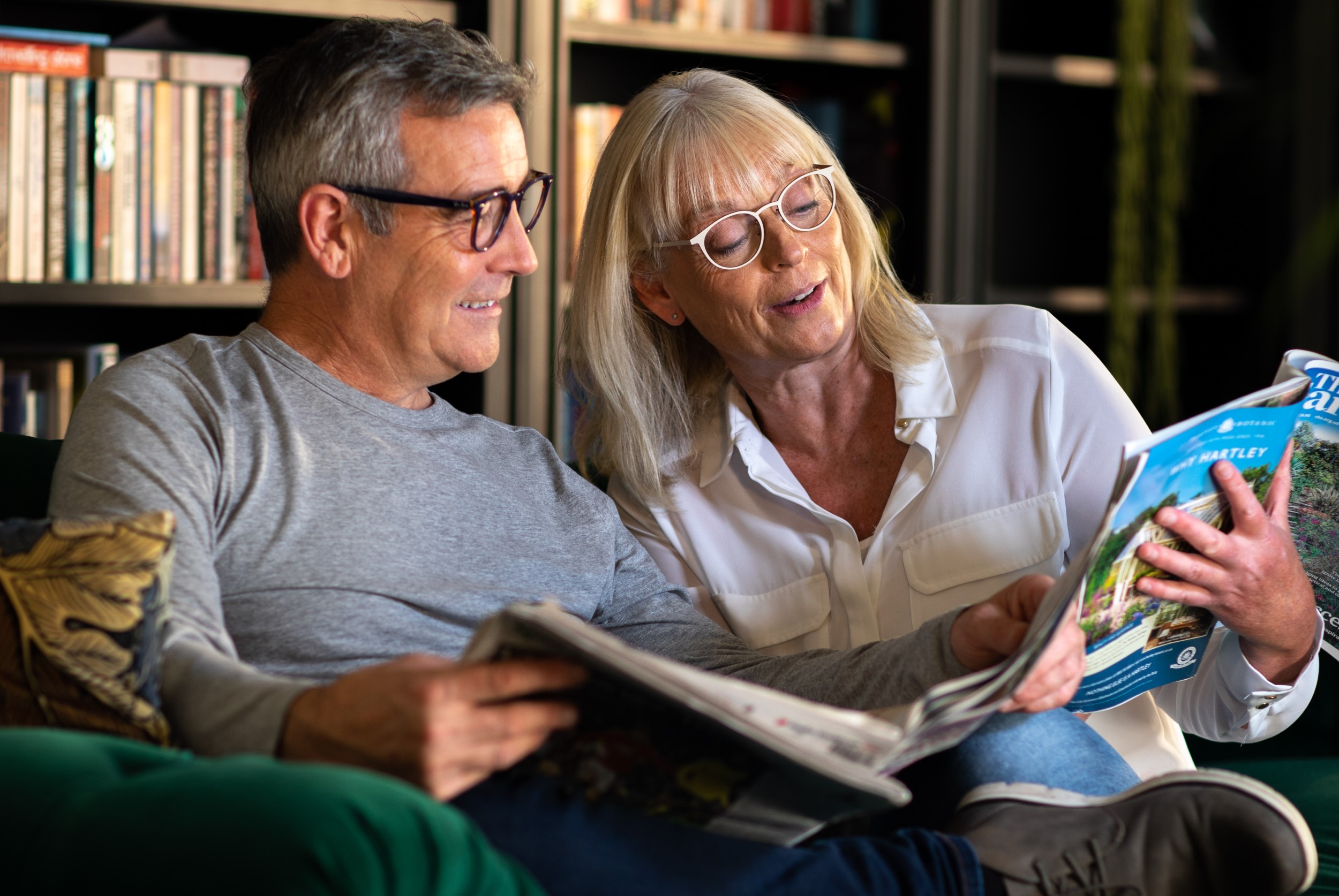 A couple sitting on a sofa and reading together.