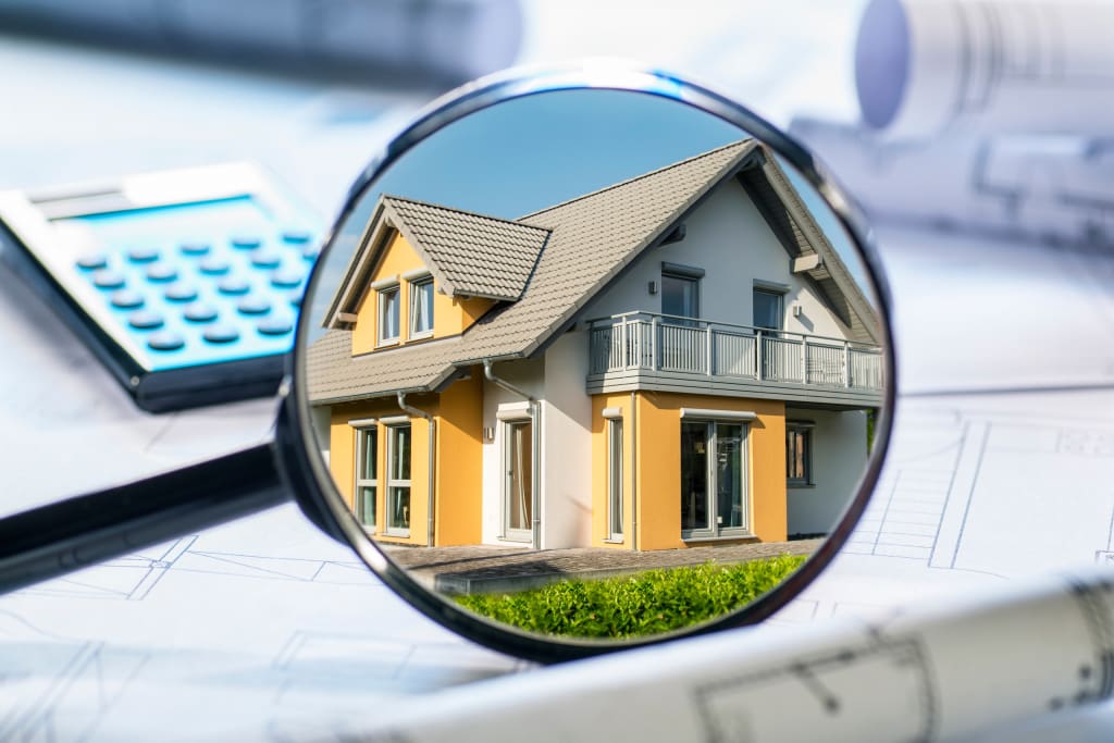 Aufnahme eines charmanten Hauses durch eine Lupe – symbolisch für Hausinspektion und Immobilieninvestition.