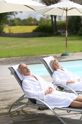 Senior couple in spa hotel relaxing in long chairs